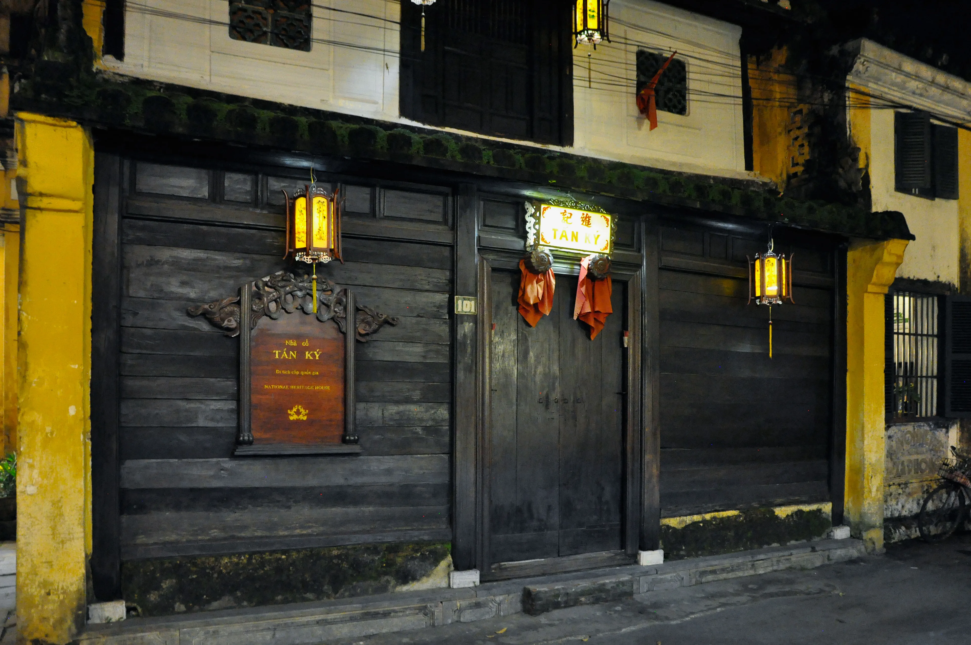 The closed timber front of Tan Ky House at night, with the number 101 and a Tấn Ký sign