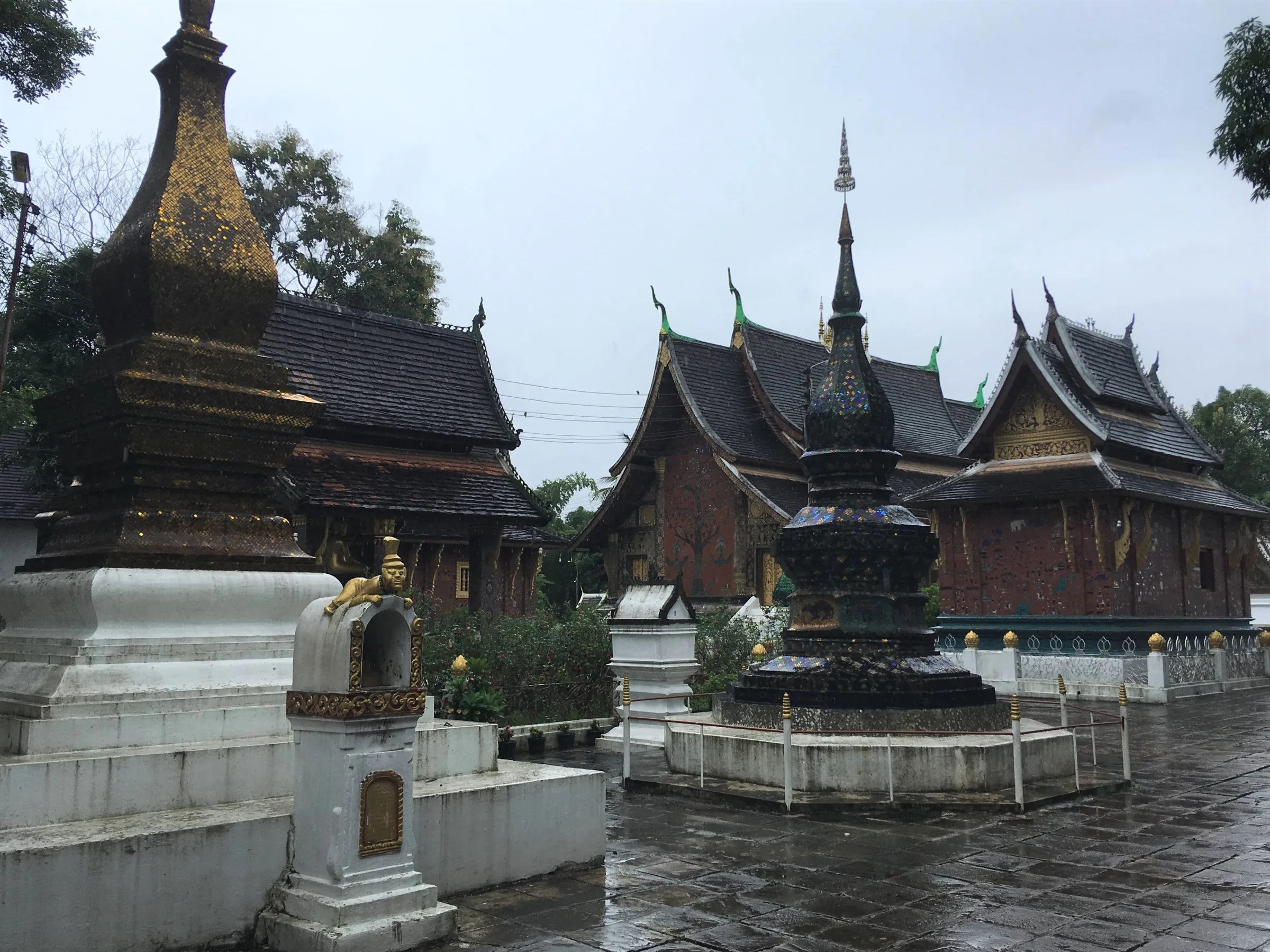 Stupas, chapels and the sim at Wat Xieng Thong after rain