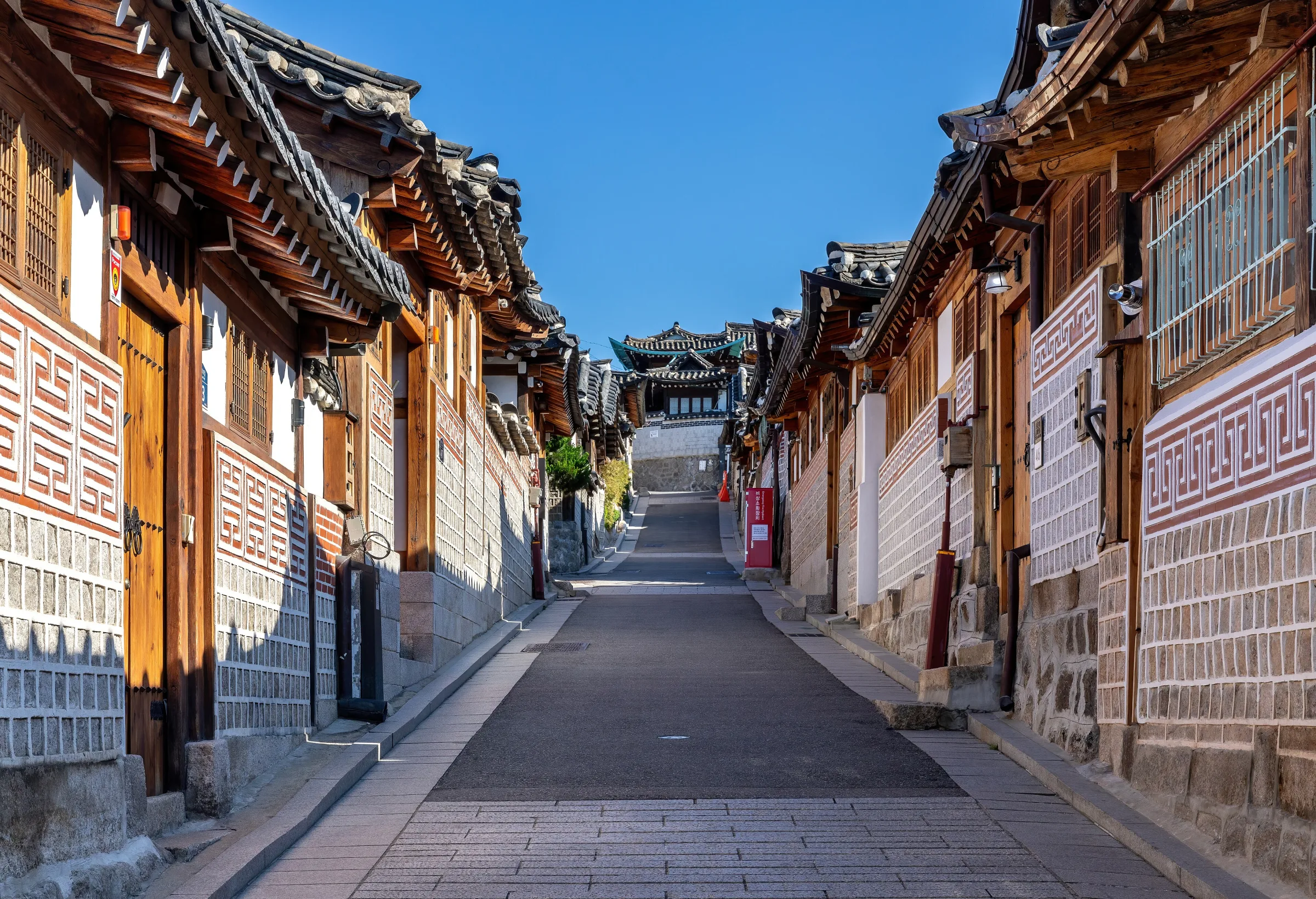 Hanok houses rising along Bukchon-ro 11-gil under a blue sky