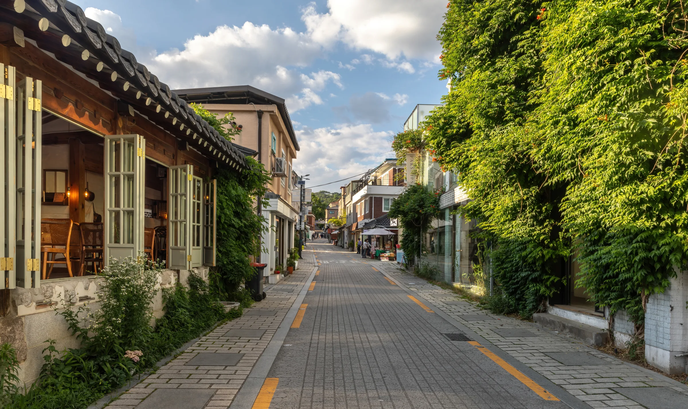 Gyedong-gil at golden hour with climbing plants and open café windows