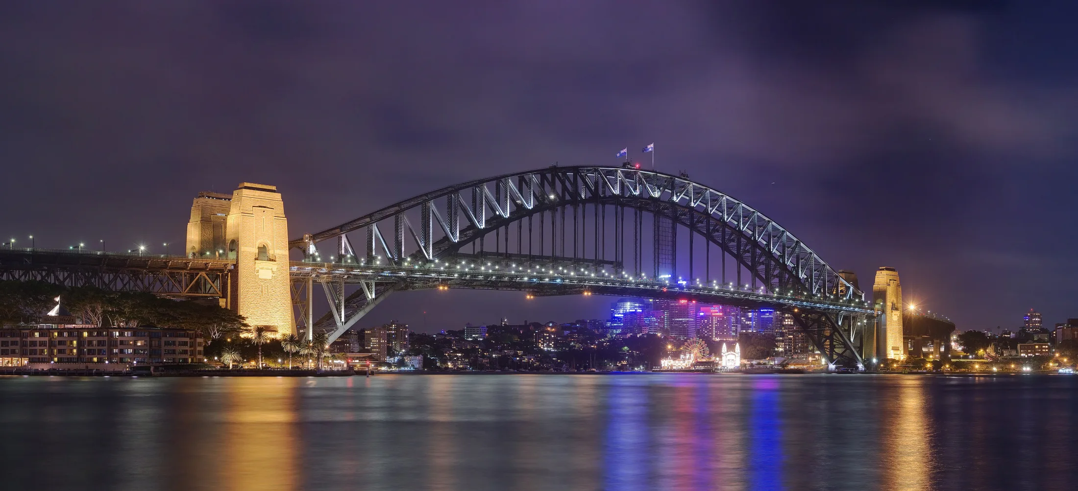 Sydney Harbour Bridge lit across Circular Quay at night